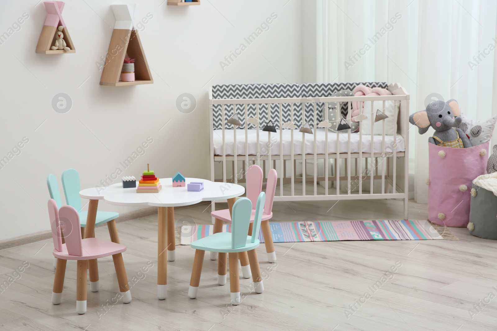 Photo of Cute baby room interior with cot and little table