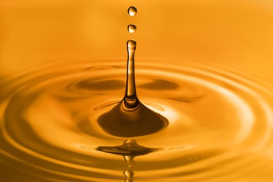 Splash of golden oily liquid with drops as background, closeup