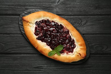 Delicious sweet cottage cheese pastry with cherry jam on black wooden table, top view