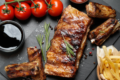 Photo of Delicious grilled ribs on black table, flat lay