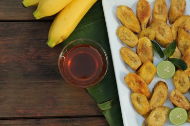 Photo of Flat lay composition with deep fried banana slices on wooden table. Space for text