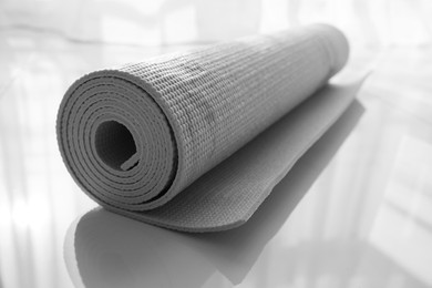 Photo of Rolled karemat or fitness mat on floor indoors, closeup