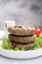 Photo of Delicious grilled vegan cutlets with lettuce on light grey table