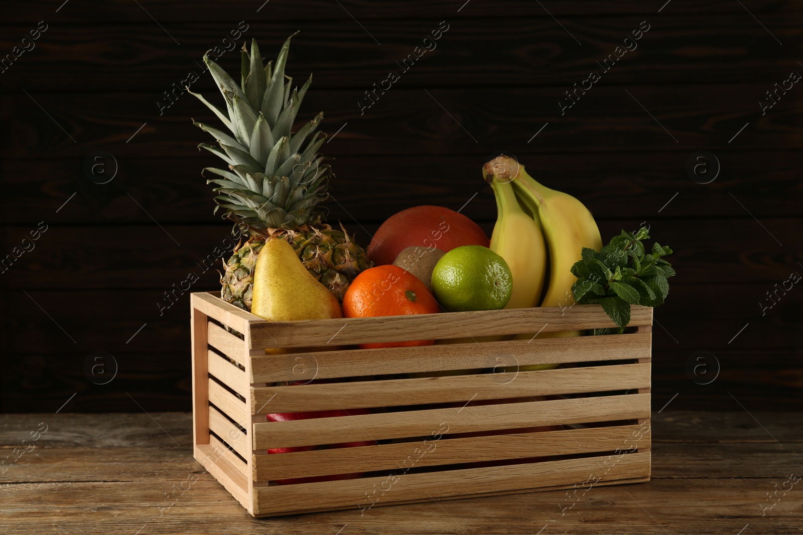 Photo of Crate with different ripe fruits on wooden table