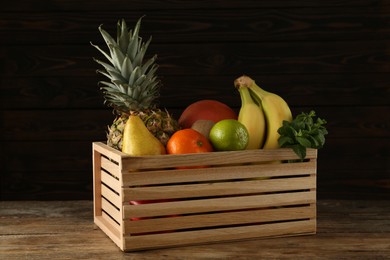 Crate with different ripe fruits on wooden table