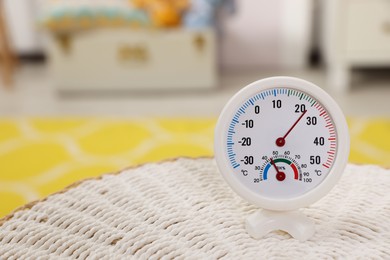 Photo of Round hygrometer with thermometer on mat in room. Space for text