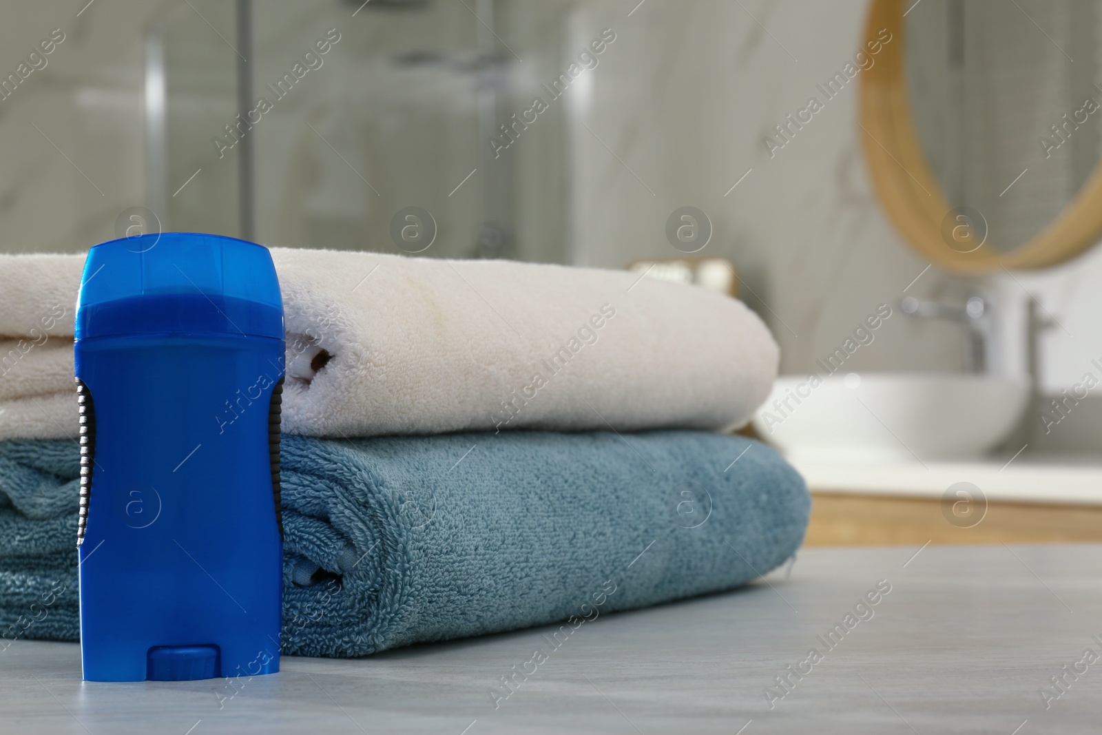 Photo of Deodorant with clean towels on table in bathroom. Space for text