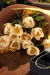 Bouquet with beautiful tulips and mimosa flowers on wooden table indoors