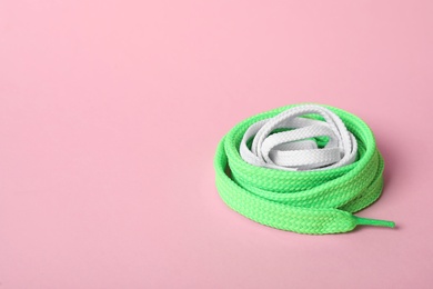Photo of Mint and white shoe laces on light pink background. Space for text