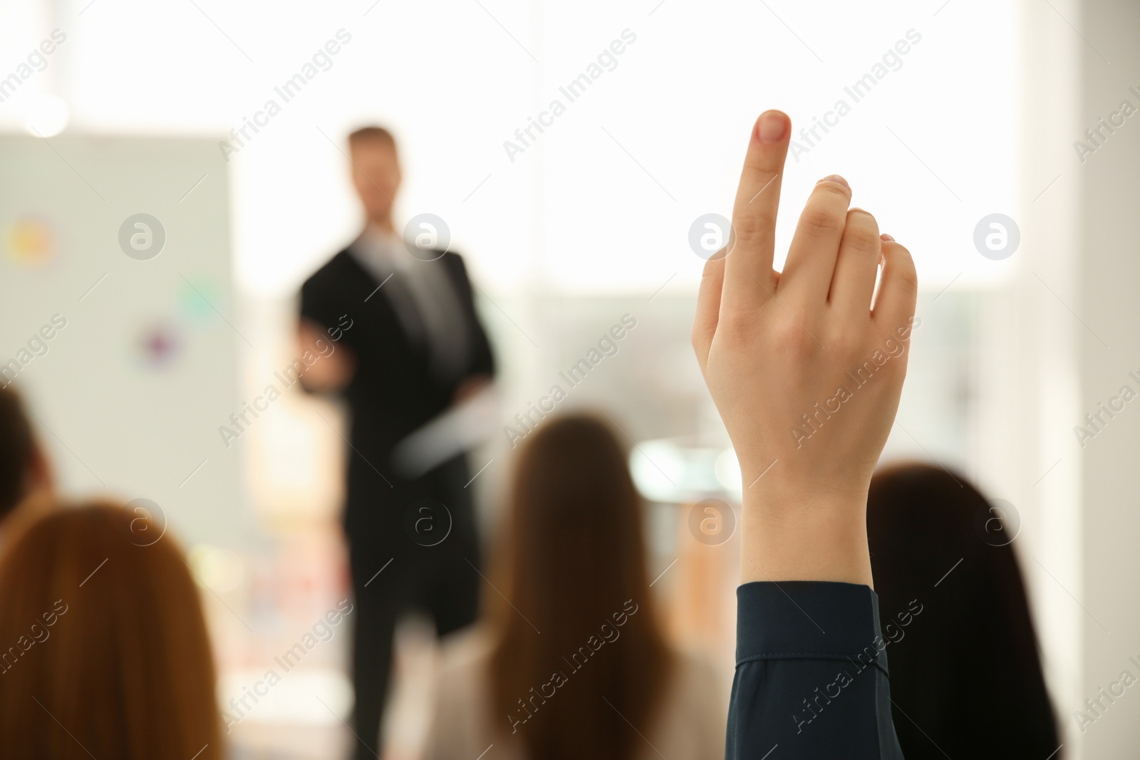 Photo of Young woman raising hand to ask question at business training indoors, closeup