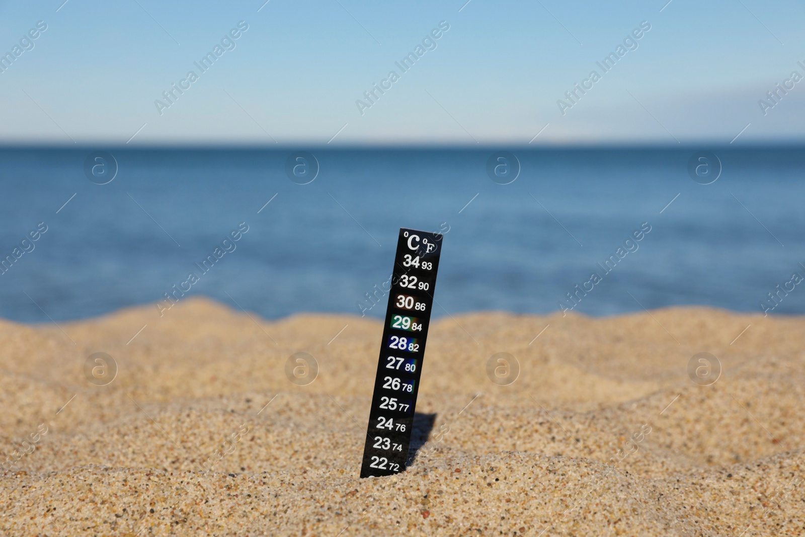 Photo of Black weather thermometer in sand near sea