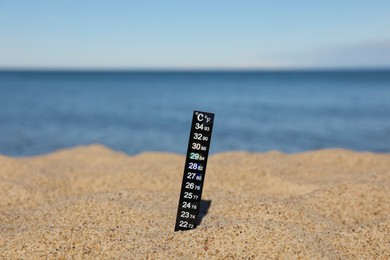 Photo of Black weather thermometer in sand near sea