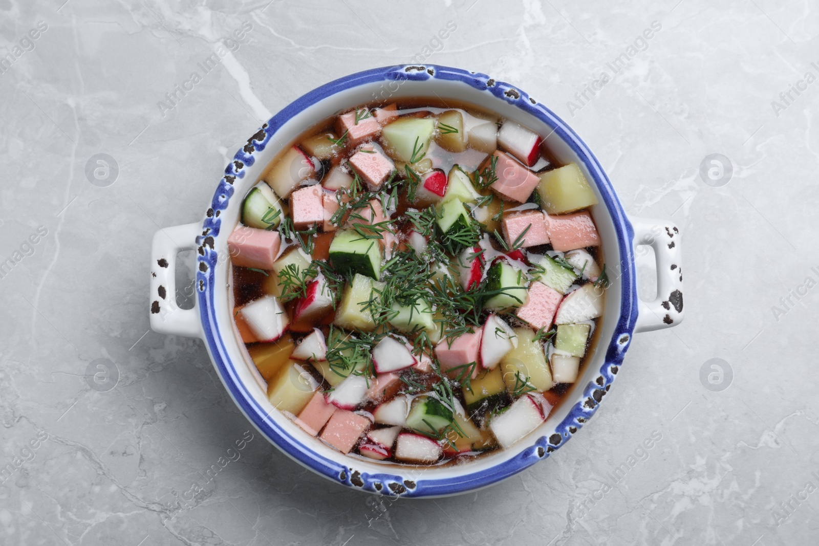 Photo of Delicious cold okroshka with kvass on grey table, top view. Traditional Russian summer soup