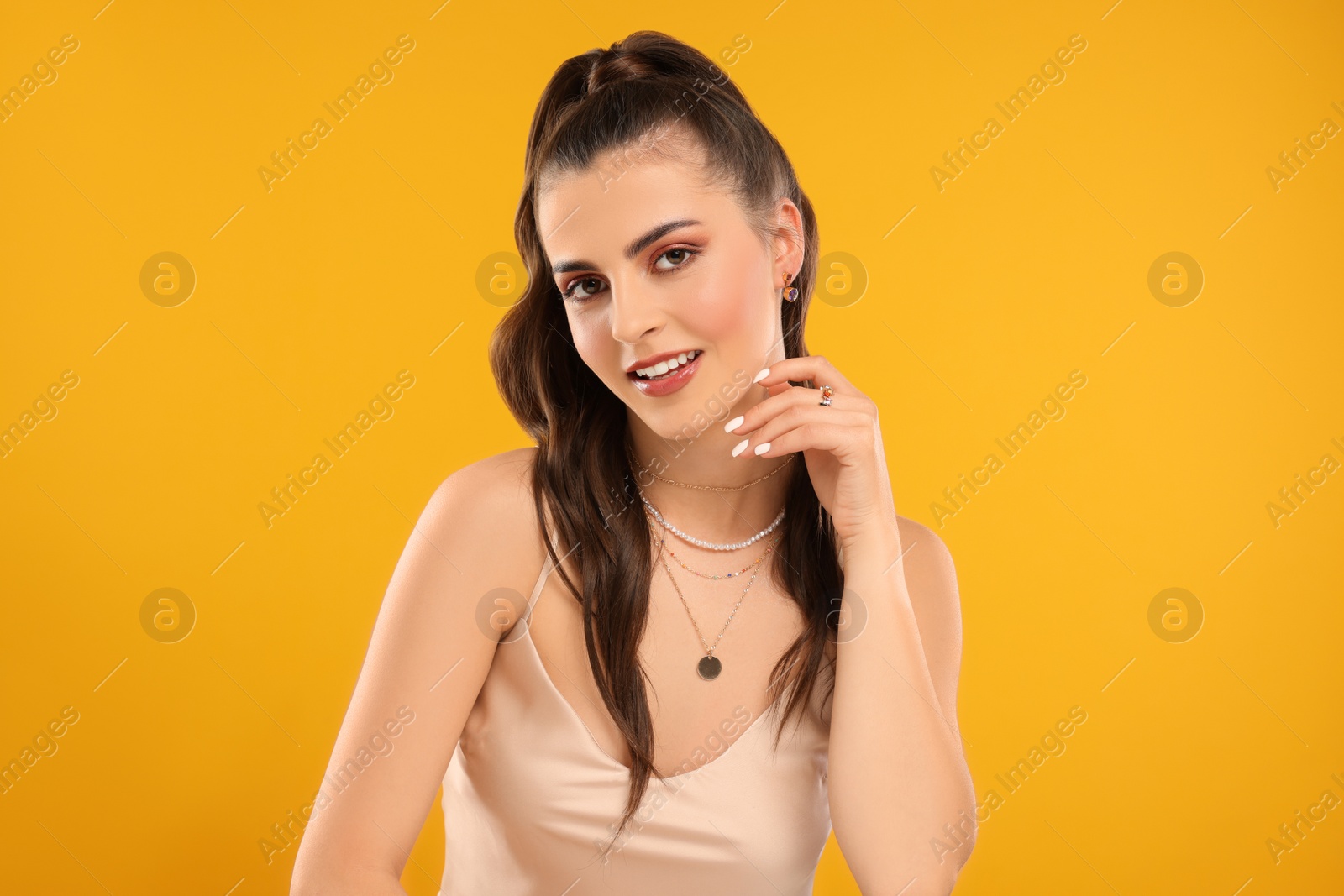 Photo of Beautiful woman with elegant jewelry on orange background