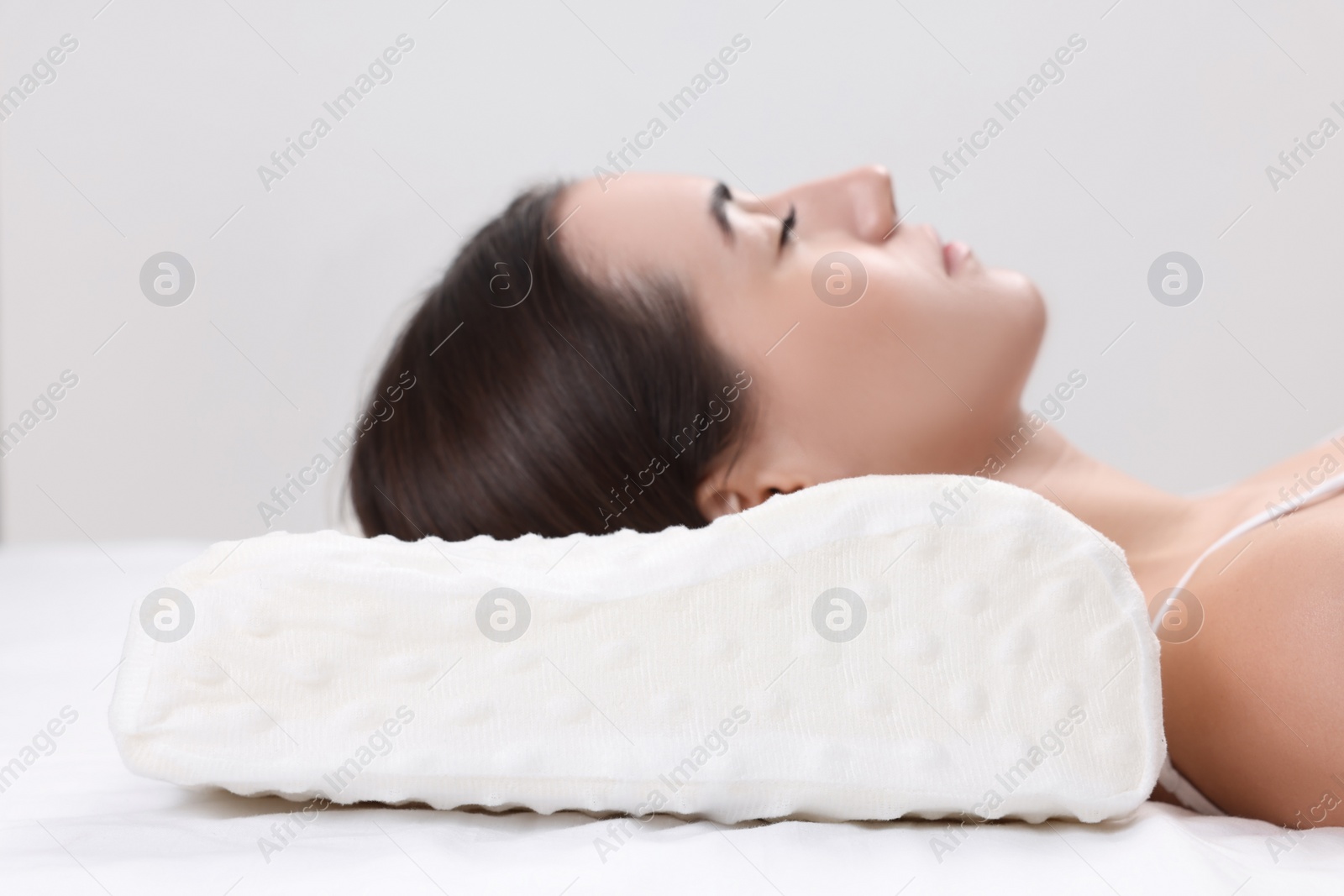 Photo of Woman sleeping on orthopedic pillow against light grey background