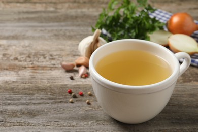 Photo of Hot delicious bouillon in cup on wooden table. Space for text