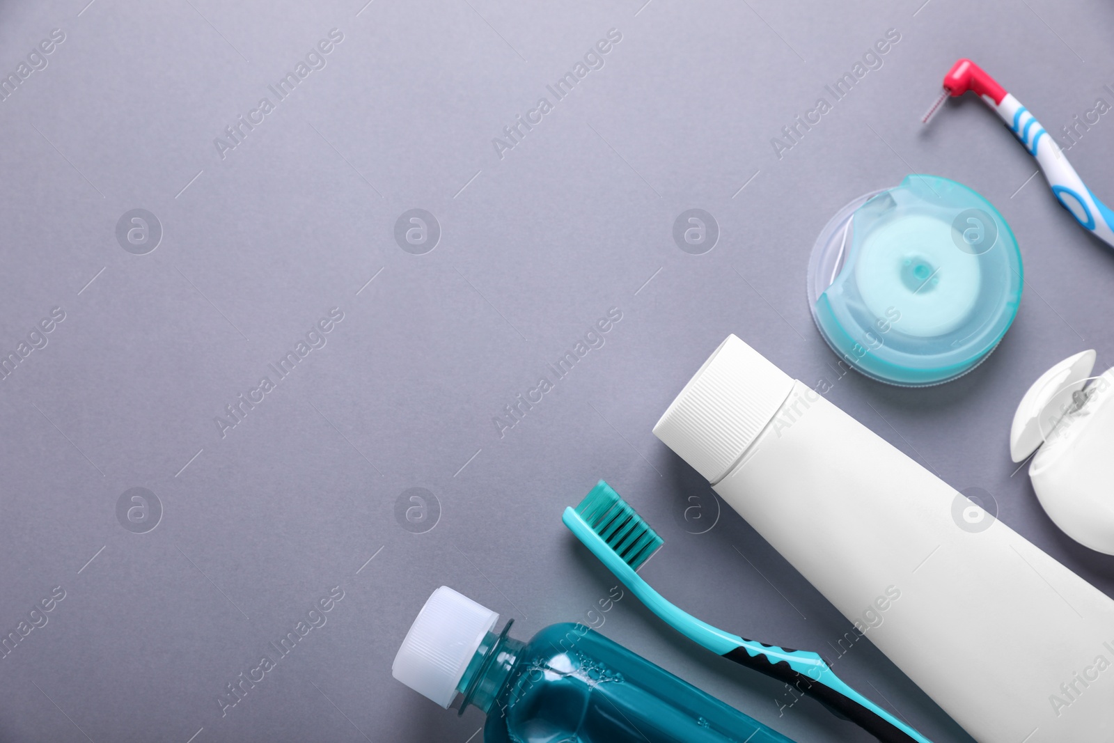 Photo of Flat lay composition with dental floss and different teeth care products on grey background. Space for text