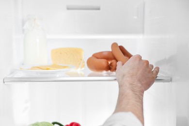 Man taking sausages out of refrigerator, closeup