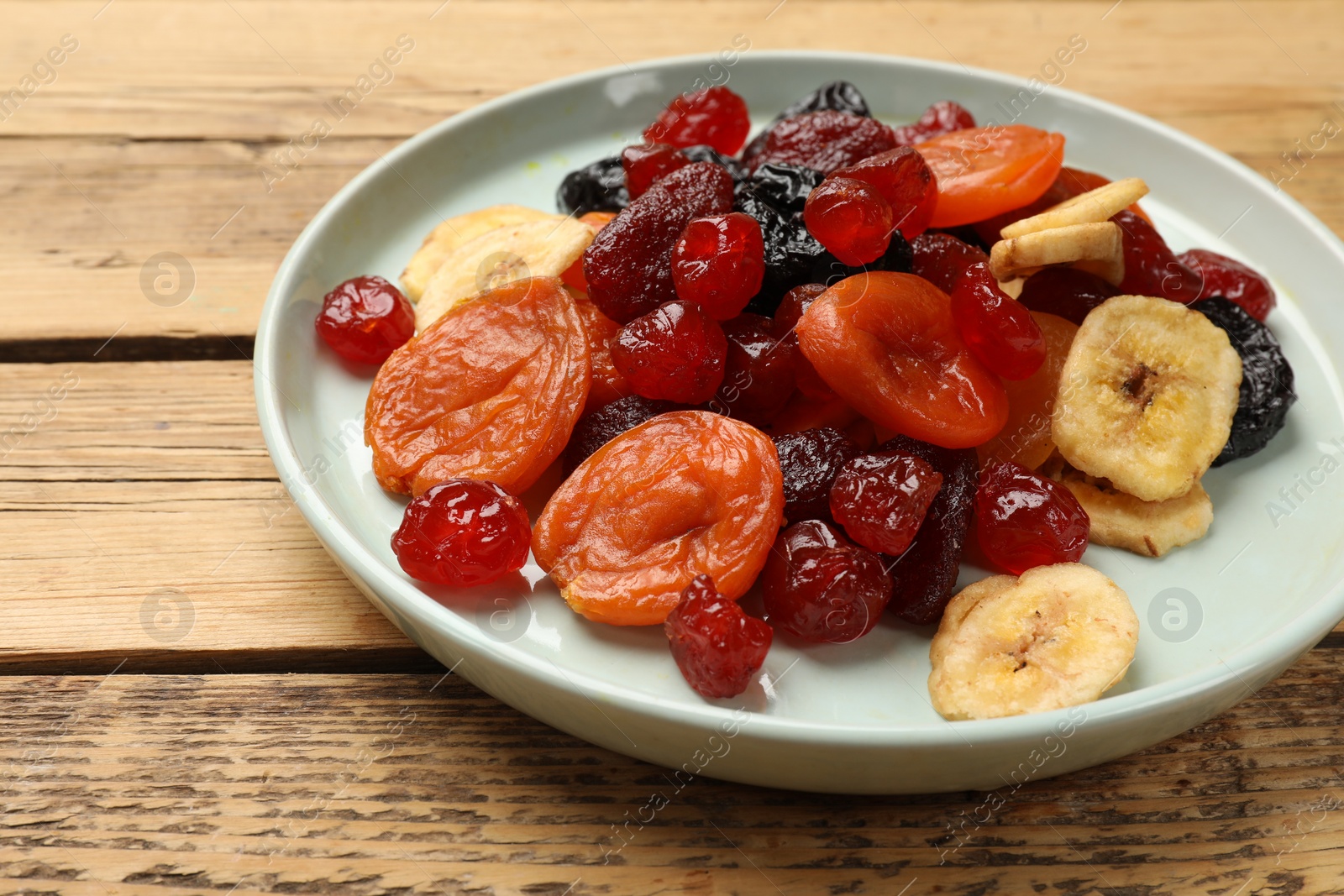 Photo of Mix of delicious dried fruits on wooden table, closeup