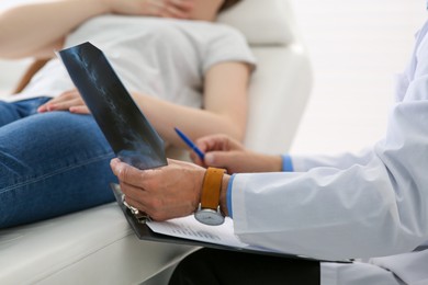 Photo of Orthopedist showing X-ray picture to patient in clinic, closeup
