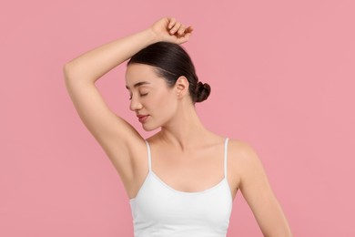 Beautiful woman showing armpit with smooth clean skin on pink background