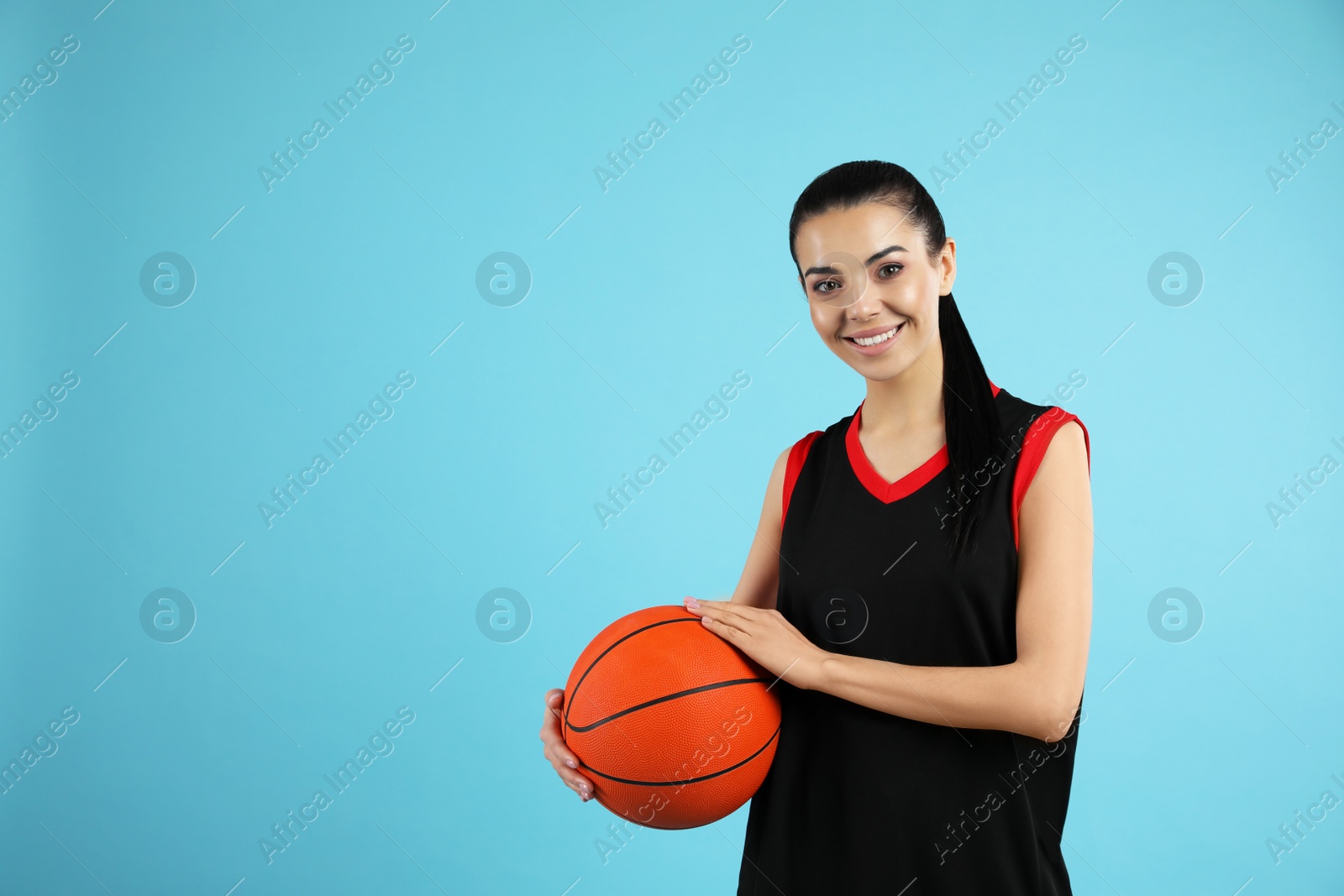 Photo of Basketball player with ball on light blue background. Space for text