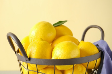 Photo of Metal basket with fresh ripe lemons on color background