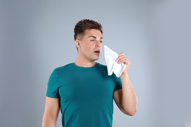 Young man suffering from allergy on grey background