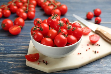 Photo of Fresh cherry tomatoes in bowl on blue wooden table