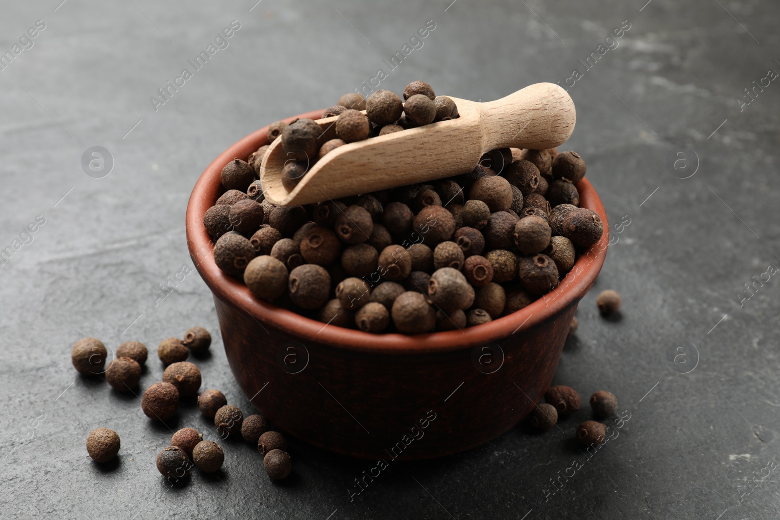 Photo of Dry allspice berries (Jamaica pepper) on black table, closeup