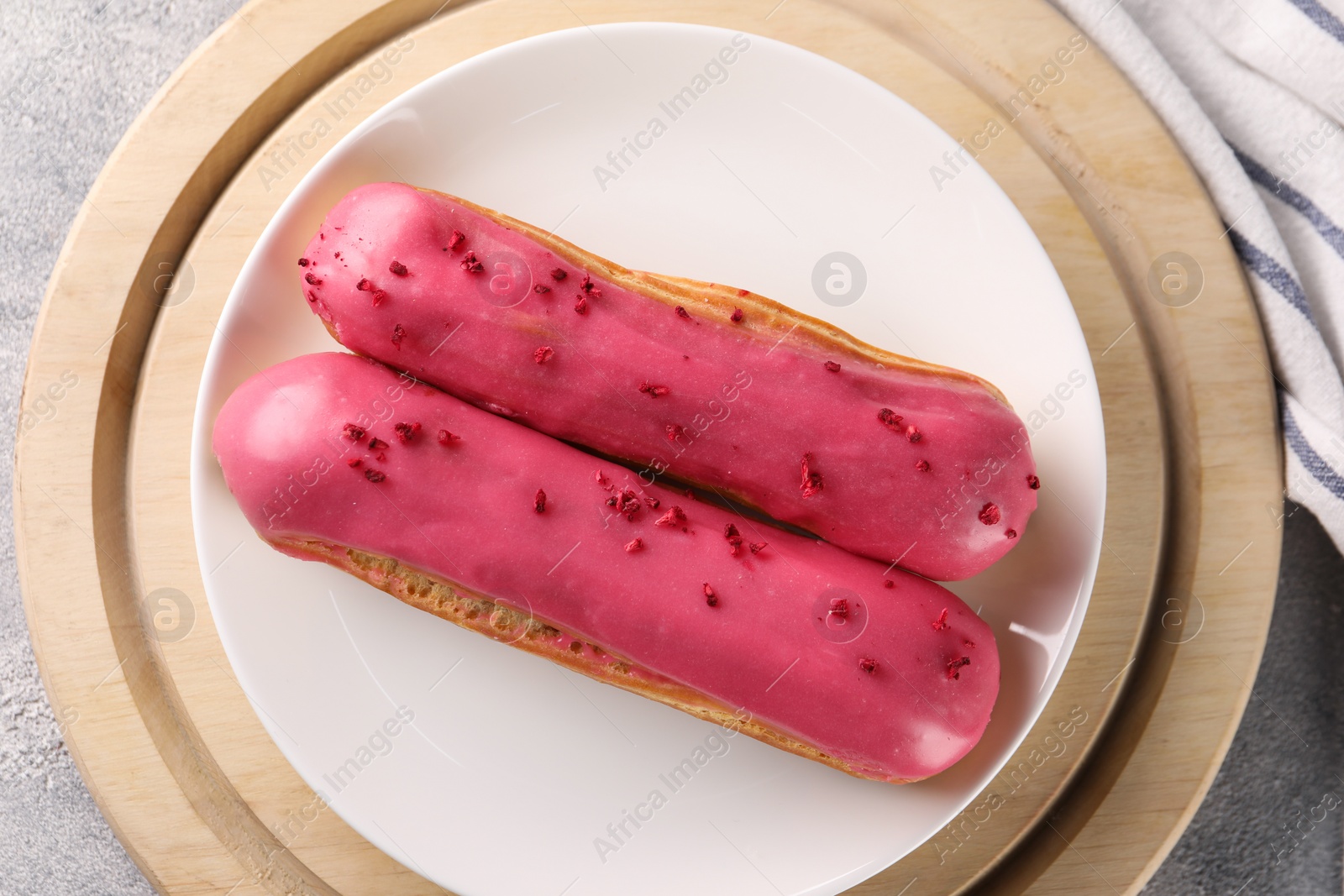 Photo of Plate with tasty glazed eclairs on grey table, top view