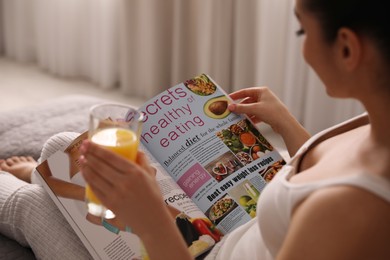 Photo of Young woman reading magazine on bed indoors