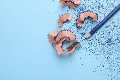 Photo of Pencil, shavings and sharpener on light blue background, flat lay. Space for text