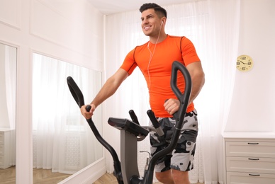Man using modern elliptical machine at home
