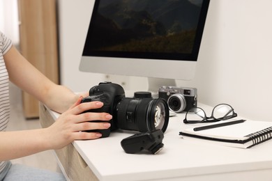 Photographer with camera at white table indoors, closeup