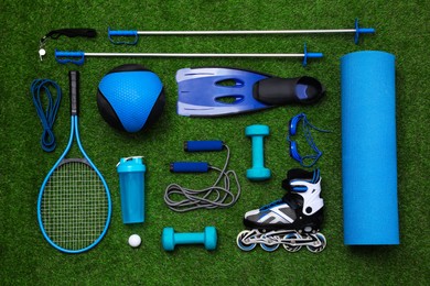 Different sport equipment on green grass, flat lay