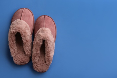 Photo of Pair of stylish soft slippers on blue background, flat lay. Space for text