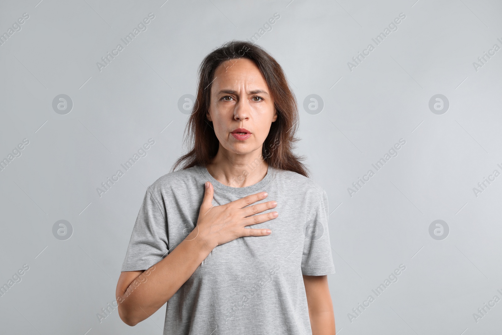 Photo of Mature woman suffering from breathing problem on light background