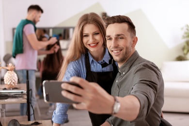 Hairdresser with happy client taking selfie in beauty salon