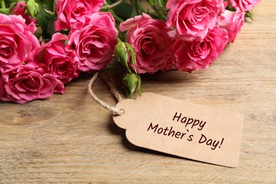 Image of Happy Mother's Day greeting label and beautiful rose flowers on wooden table