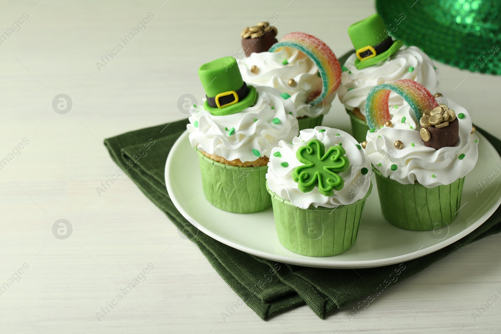 Photo of St. Patrick's day party. Tasty festively decorated cupcakes on white table, closeup. Space for text