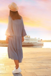 Young woman walking on pier at sunset light