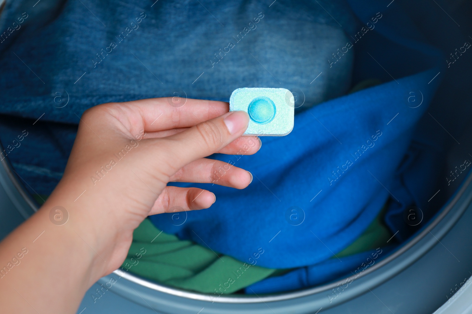 Photo of Woman putting water softener tablet into washing machine, closeup