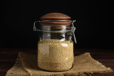 Jar with white quinoa on wooden table