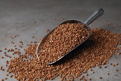 Photo of Metal scoop with uncooked buckwheat on table