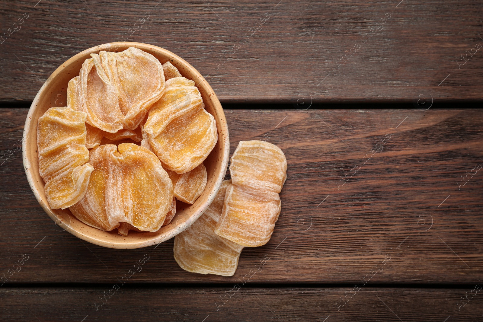 Photo of Delicious dried jackfruit slices on wooden table, flat lay. Space for text