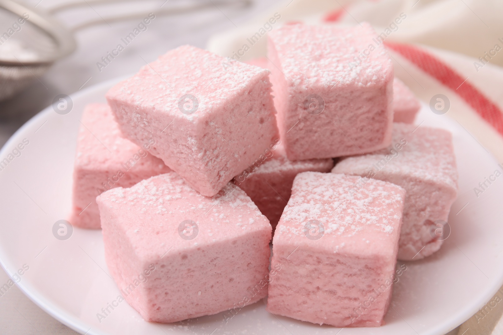 Photo of Plate of delicious sweet marshmallows with powdered sugar on table, closeup