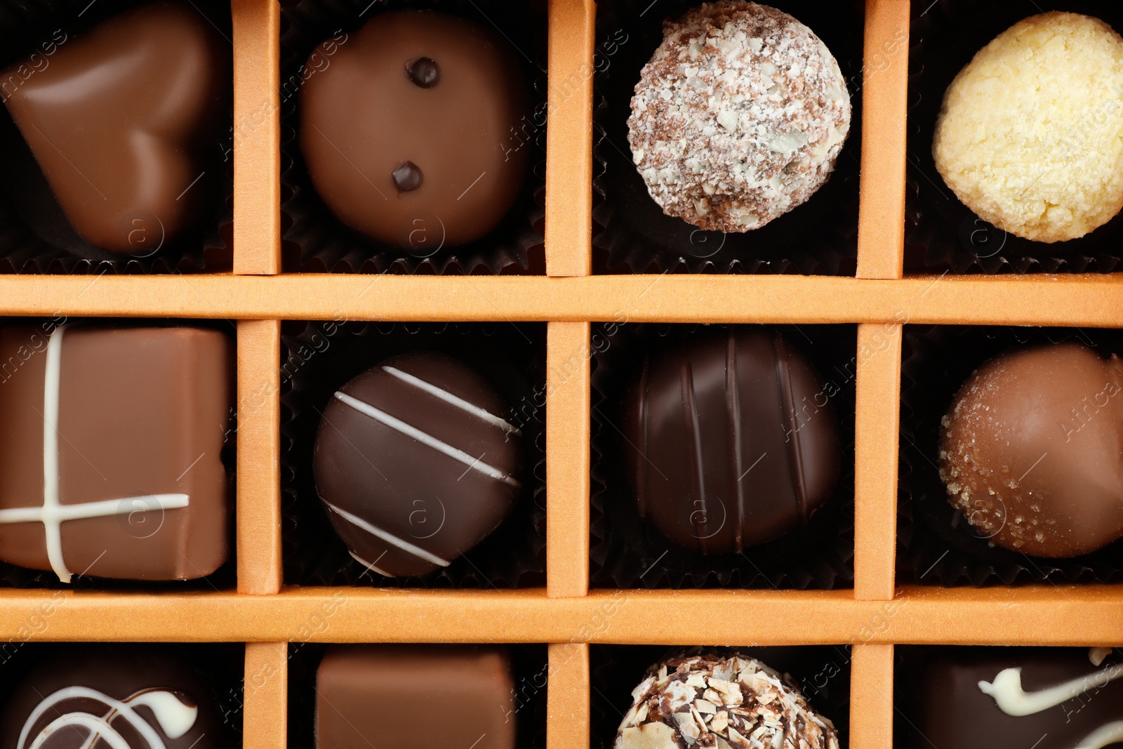 Photo of Box with different chocolate candies as background, top view