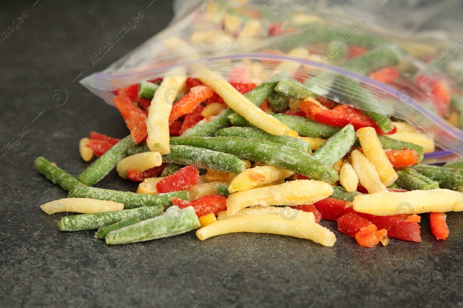 Photo of Zip bag with different frozen vegetables on grey table, closeup