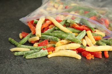 Zip bag with different frozen vegetables on grey table, closeup